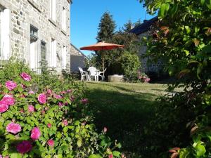 un cortile con tavolo, ombrellone e fiori di Bienvenue chez Fanny a Bussières