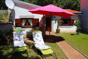two chairs and an umbrella in a yard at One-Bedroom Holiday Home in Povile I in Povile
