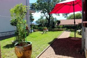 a plant in a pot next to a red umbrella at One-Bedroom Holiday Home in Povile I in Povile