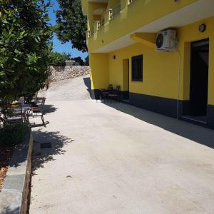 a yellow building with chairs and a patio at Apartment Vrbnik 7 in Vrbnik