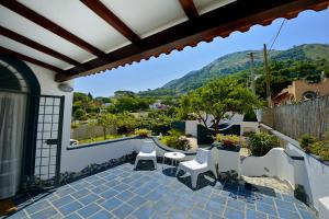 a patio with white chairs and a view of a mountain at BnB Le Isole in Ischia