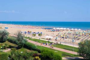 una playa con mucha gente y sombrillas en Apartments in Bibione 24391, en Bibione