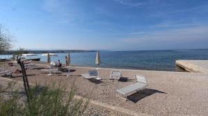 a group of chairs and umbrellas on a beach at Apartment Malinska, Krk 19 in Malinska