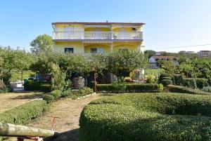 a yellow house with a balcony on top of a garden at Apartment Lopar, Primorje-Gorski Kotar 2 in Lopar