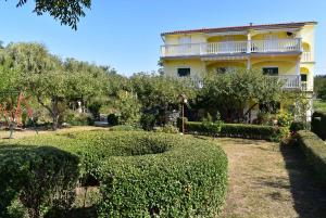 a yellow house with a large bush in front of it at Apartment Lopar, Primorje-Gorski Kotar 2 in Lopar