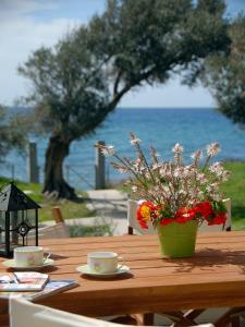 - une table en bois avec deux tasses et des fleurs dans l'établissement Melinda Holiday House, à Plomári