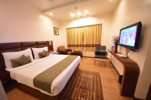 um quarto com uma cama grande e uma televisão de ecrã plano em The Legend Inn @Nagpur em Nagpur