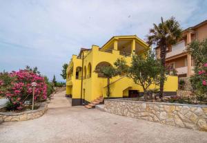 a yellow house with some flowers in front of it at Apartment Vrbnik 1 in Vrbnik +12 photos