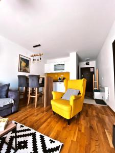 a living room with a yellow chair and a kitchen at La Siesta Apartment in Zlatibor