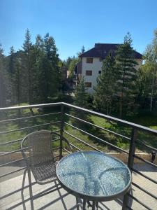 a glass table and a chair on a balcony at La Siesta Apartment in Zlatibor