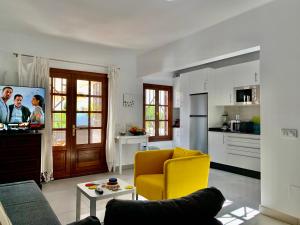 ein Wohnzimmer mit einem gelben Stuhl und einer Küche in der Unterkunft Pequeño Paraíso Lanzarote, modernes Ferienhaus am Meer für 4 in Playa Honda