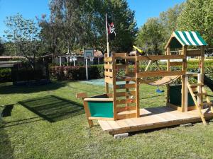 a wooden playground with a slide and a basketball hoop at Camping Smeraldo in Trevignano Romano