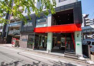 un negozio in una strada con una facciata rossa e nera di Hotel New Gaea Yakuin a Fukuoka