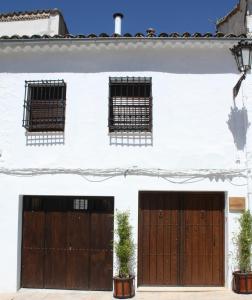 ein weißes Haus mit zwei Holztüren und zwei Fenstern in der Unterkunft Barbacana, dieciocho in Baeza