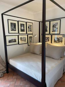 a bedroom with a four poster bed with pictures on the wall at Casa De S'Arca in Torre Dei Corsari