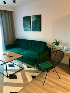 a living room with a green couch and a chair at Apartament na Skrzypka in Cieszyn