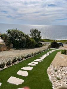 a pathway with grass and rocks next to the ocean at Casa De S'Arca in Torre Dei Corsari