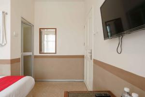 a bedroom with a bed and a television on a wall at RedDoorz near Plaza Botania 1 Batam in Batam Center