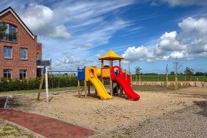a playground with a slide in the sand at Ferienwohnungen am Museumshof in Fehmarn
