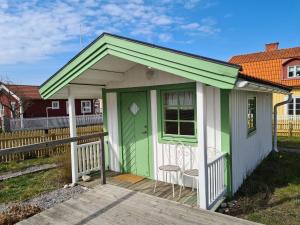 un pequeño cobertizo verde y blanco con porche en Missionshuset Bed & Breakfast, en Sandhamn