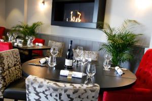 een eetkamer met een tafel met wijnflessen en stoelen bij Hôtel De La Plage in Damgan