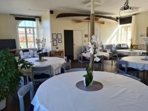 uma sala com mesas e cadeiras com mesas brancas e flores em Missionshuset Bed & Breakfast em Sandhamn