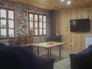 ein Wohnzimmer mit einem Tisch und einem TV an der Wand in der Unterkunft Casa Rural Marineta Casiana - Riópar in Riópar