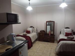 a hotel room with two beds and a television at KIHARA GUESTHOUSE in Bethlehem