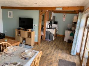 a living room with a table and a television at Manordaf Holiday Cottage in St Clears