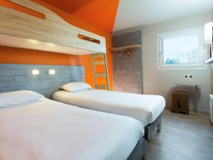 - 2 lits dans une chambre aux murs orange dans l'établissement Ibis Budget Fresnes Orly, à Fresnes