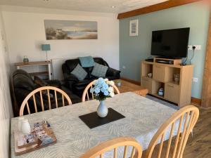 a living room with a table with a vase of flowers at Manordaf Holiday Cottage in St Clears