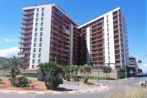 two tall buildings with palm trees in front of a street at EDIFICIO ALGAIDA - NEW VISTA MONTAÑA - PLAYA DE LA CONCHA in Oropesa del Mar