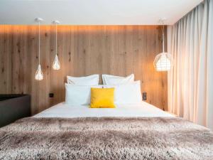 - une chambre avec un grand lit et 2 oreillers jaunes dans l'établissement Mercure Valence, à Valence