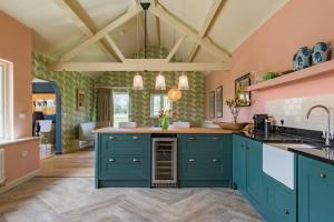 a kitchen with green cabinets and a ceiling with beams at Snipe Barn in Aston
