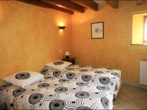 1 dormitorio con 1 cama con edredón blanco y negro en Gîte des 3 Hiboux, en Mondon