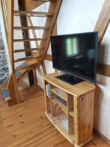 a television on a wooden stand in a room at La maison dans les prés in Labaroche