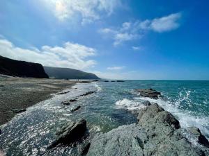 une plage avec des rochers et l'océan par une journée nuageuse dans l'établissement Chalet Kiss of the Sea, à Aberystwyth