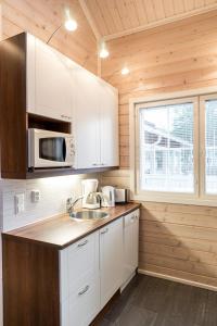 eine Küche mit einer Spüle und einer Mikrowelle in der Unterkunft Sarahovi A in Kalajoki