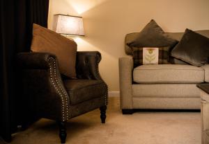 
a living room with a couch, chair and a lamp at Nevis Bank Inn in Fort William
