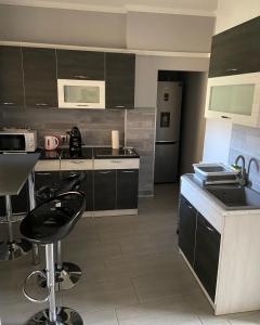 a kitchen with black cabinets and a counter with stools at CentRoom Apartman in Sátoraljaújhely