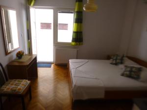 a bedroom with a bed and a chair and a window at Haus Pehar in Baška Voda