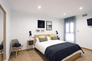 una camera bianca con un grande letto e una sedia di Rem Apartamentos a Torre-Pacheco