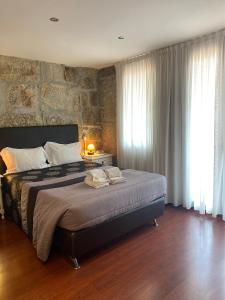a bedroom with a large bed with a stone wall at PORTO RICO STUDIOS in Porto