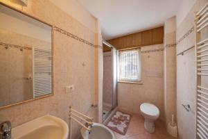 a bathroom with a sink and a toilet and a mirror at Appartamento Primavera 3 in Moena