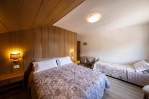 a bedroom with two beds in a room with wooden walls at Appartamento Primavera 3 in Moena