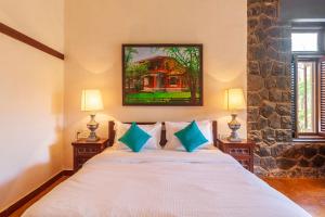 1 dormitorio con 1 cama blanca y 2 lámparas en StayVista at Villa Amarillo with Pvt Pool, Gazebo & Alfresco Dining, en Alibaug