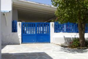 a blue gate in front of a white house at Παραλια Γαυρίου in Gavrion