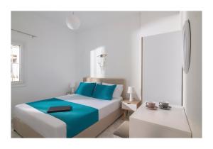 a white room with a bed with blue pillows at Kastri Mare Sea View Residences by Estia in Keratokampos