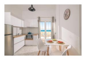 eine Küche mit einem Tisch und Stühlen sowie eine Küche mit Meerblick in der Unterkunft Kastri Mare Sea View Residences by Estia in Keratókambos