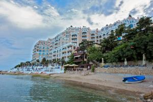 a large building on a beach next to a body of water at Dreams in La Mer in Golden Sands